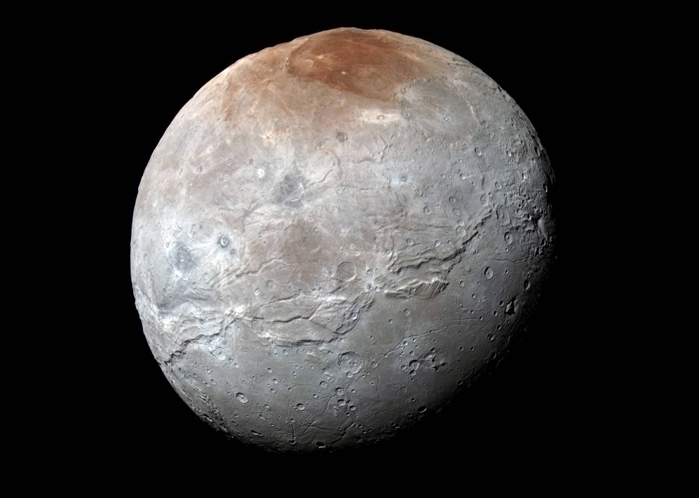 An enhanced color view of Pluto’s largest moon, Charon. Scientists have learned that reddish material in the north (top) polar region is chemically processed methane that escaped from Pluto’s atmosphere onto Charon. Credits: NASA/JHUAPL/SwRI
