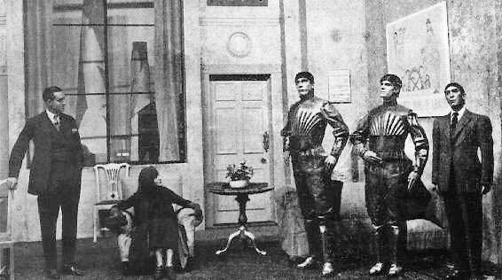 old black and white photo in a living room with three stiff robot people with two regular humans