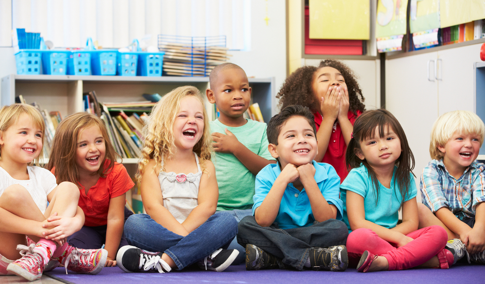 a group of children sitting and smiling in a classroom