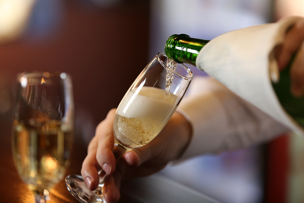 someone pouring champagne into a flute glass