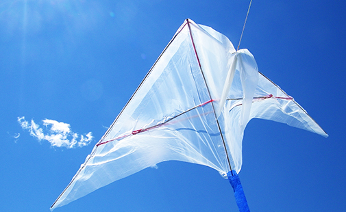 Kite made out of plastic bags flies against a blue sky on a windy day