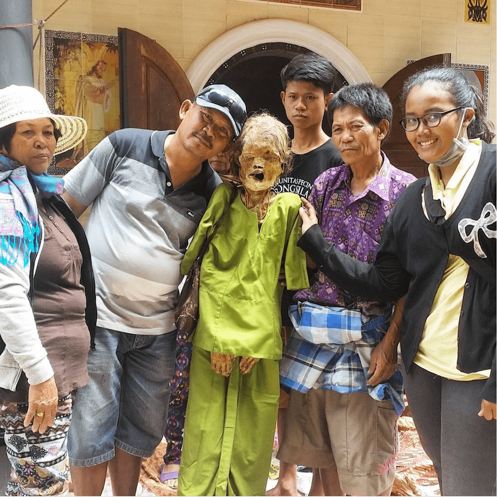 family in indonesia poses with mummified loved one