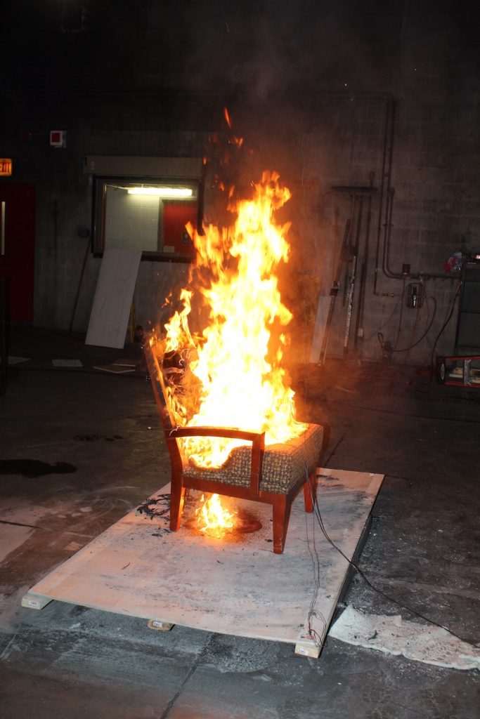 a wooden chair with a polyurethane foam pad on fire