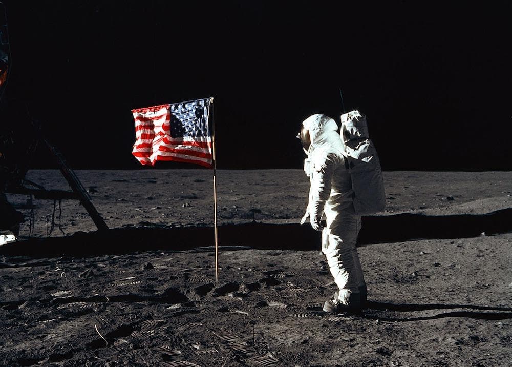 aldrin in his spacesuit on the moon in color next to the american flag