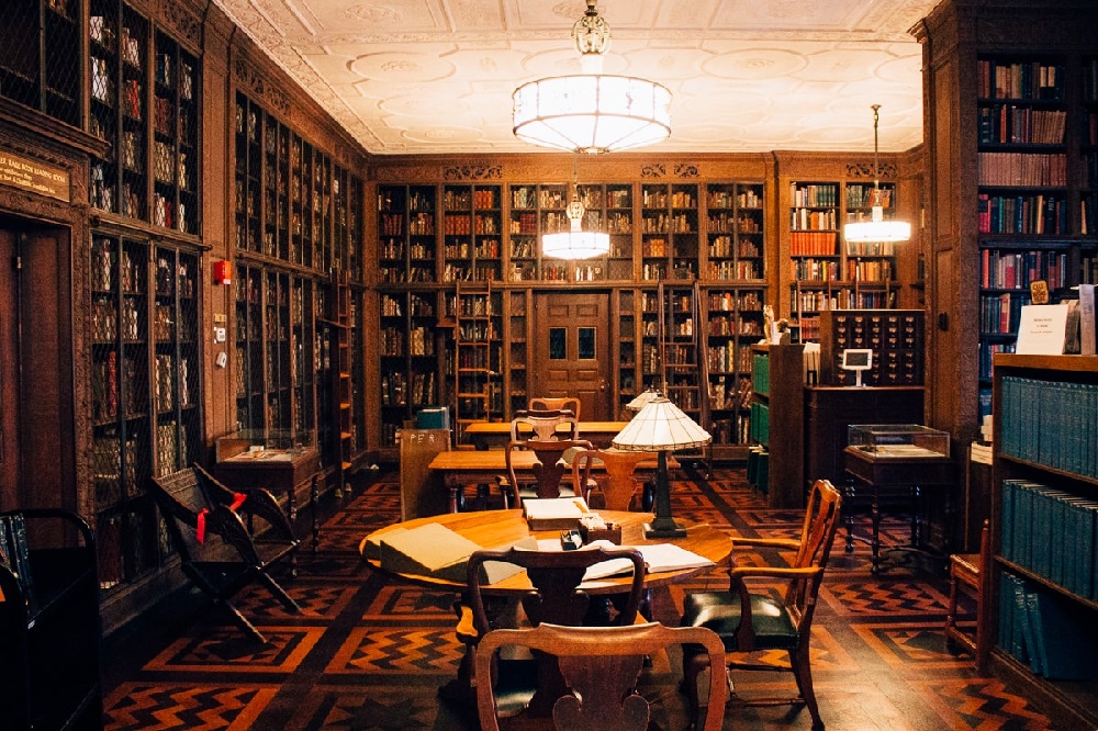 wide shot of new york academy of medicine's reading room, floor to ceiling shelves lined with old books and artifacts