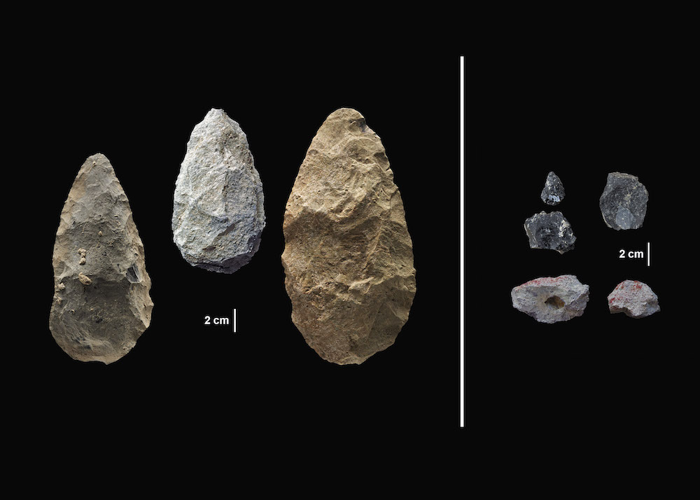 large and small stone-cutting tools against black background