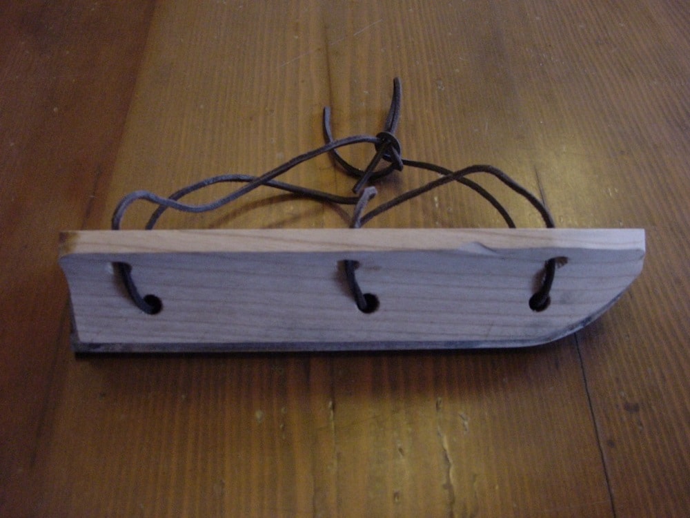 thick wooden skate with strings and thin blade