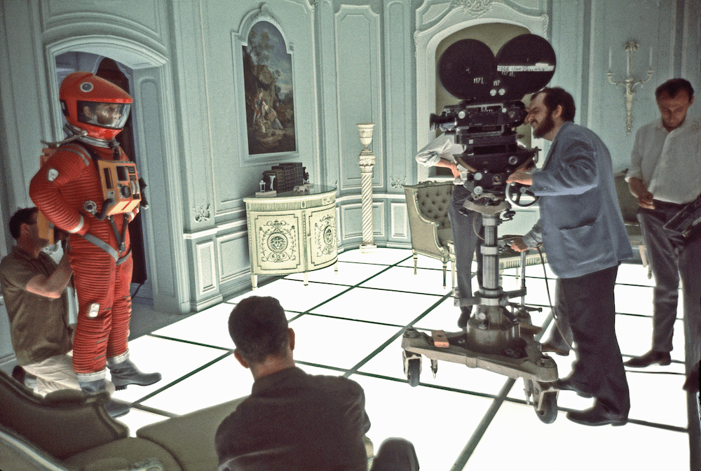 the film crew sets up in an opulent hotel room with one of the astronauts standing in his suit