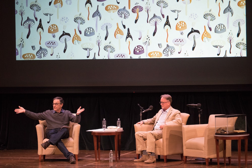 two people onstage with a photo background of mushrooms