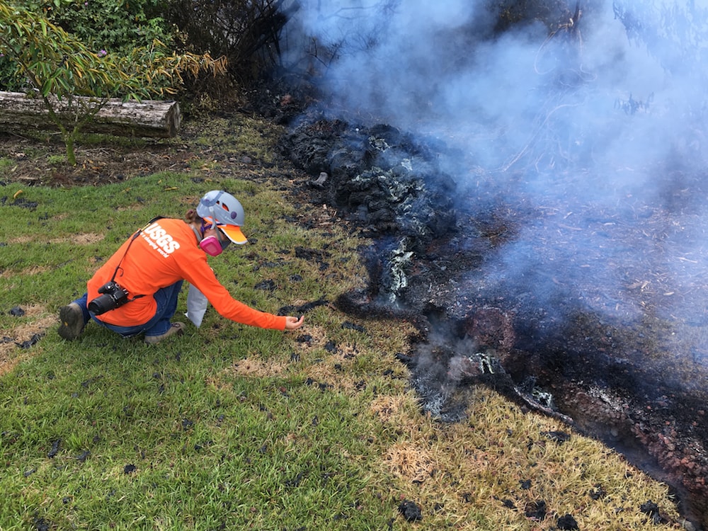 person with gas mask carefully samples lava