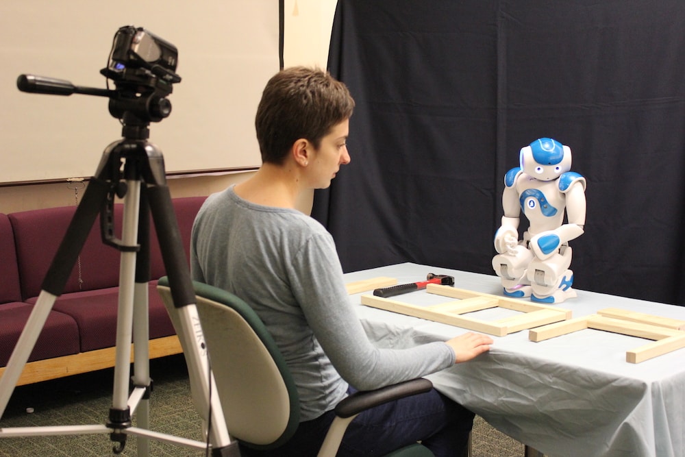 a researcher studying a small humanoid robot