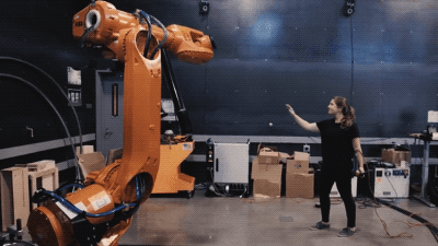 an orange robotic arm responds to the movement of a scientist's gestures