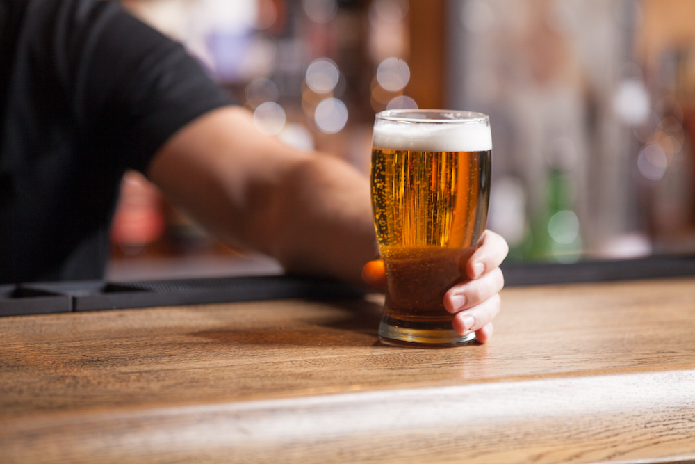 bartender pushing glass of beer across the bar