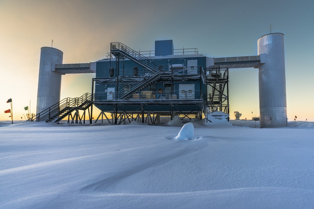 an isolated station out in a snowy field of antarctica at sunset