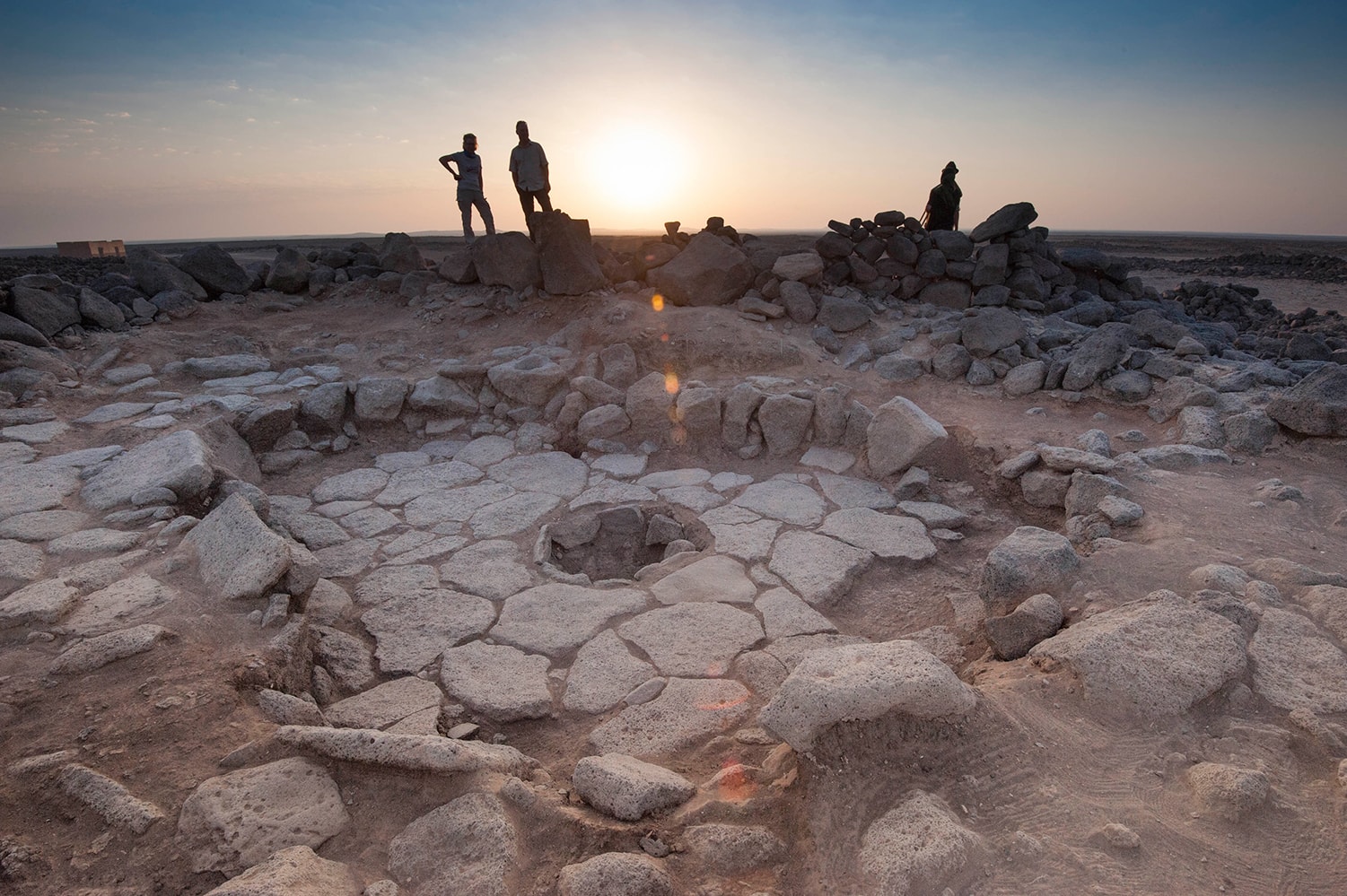 Researchers standing around stone oven structure