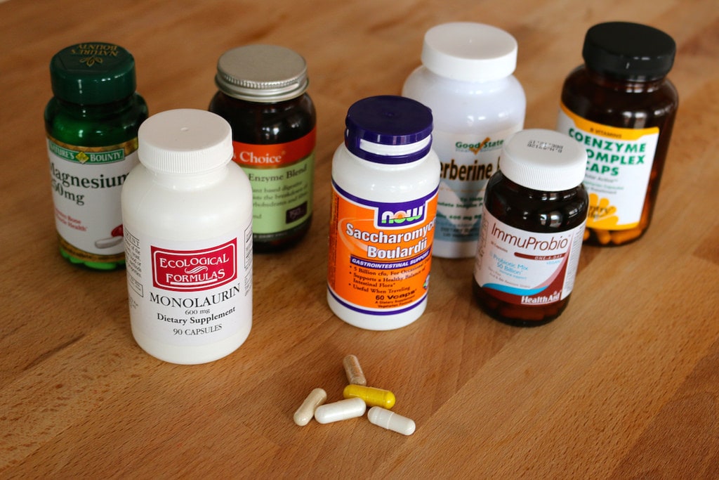 seven different pill bottles with five pills in front of them