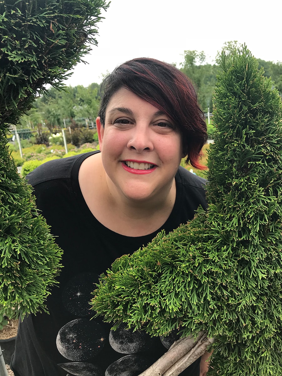 Amy Cataldo's smiling face between two topiary shrubs