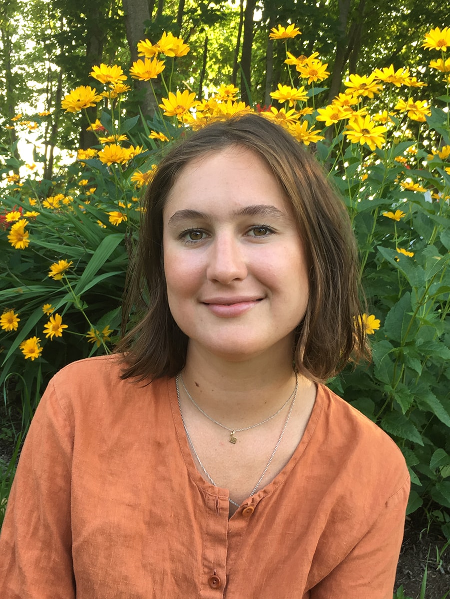 Molly Adams standing in front of a background of yellow flowers