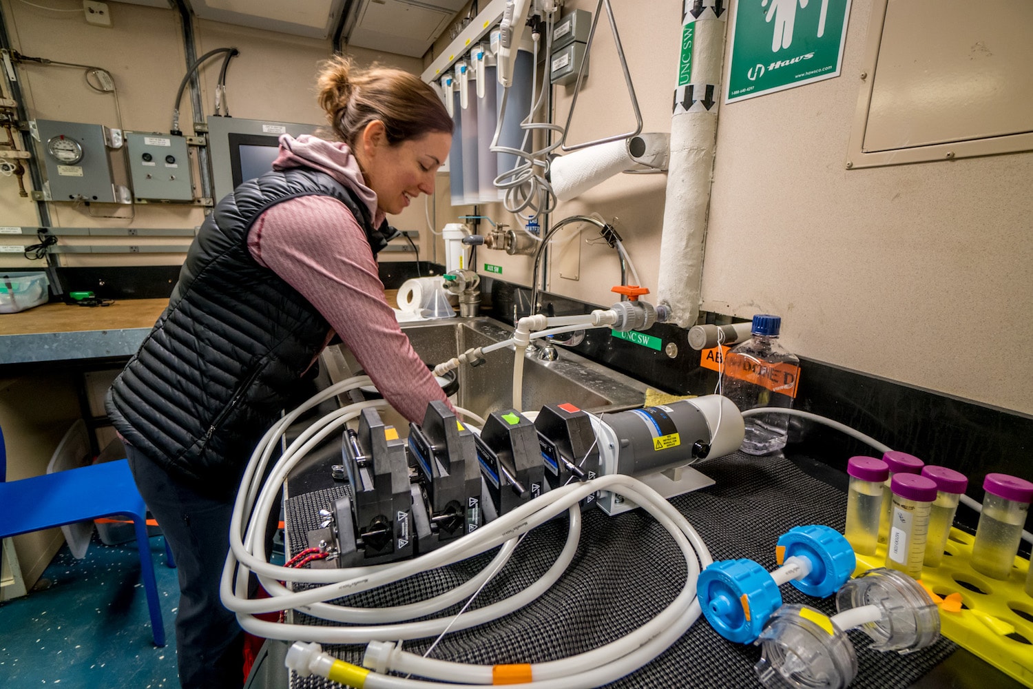 a woman in a lab next to a sink working on a piece of equipment