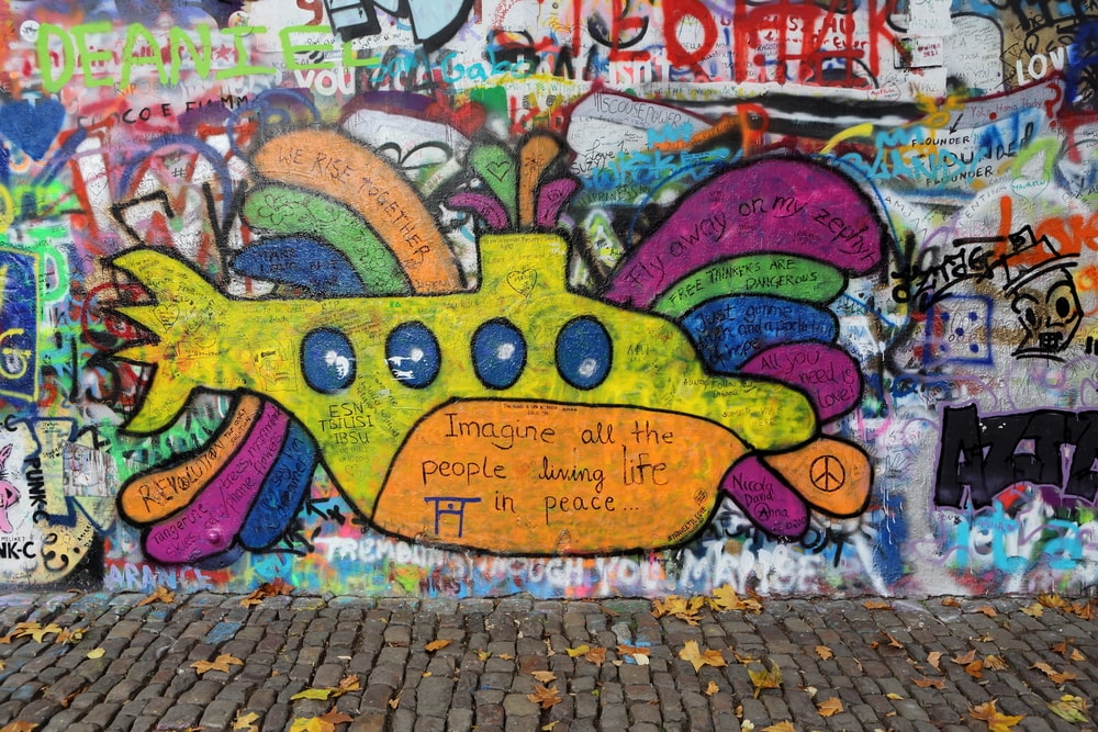 a wall with graffiti and a yellow submarine in the center with beatles lyrics around it