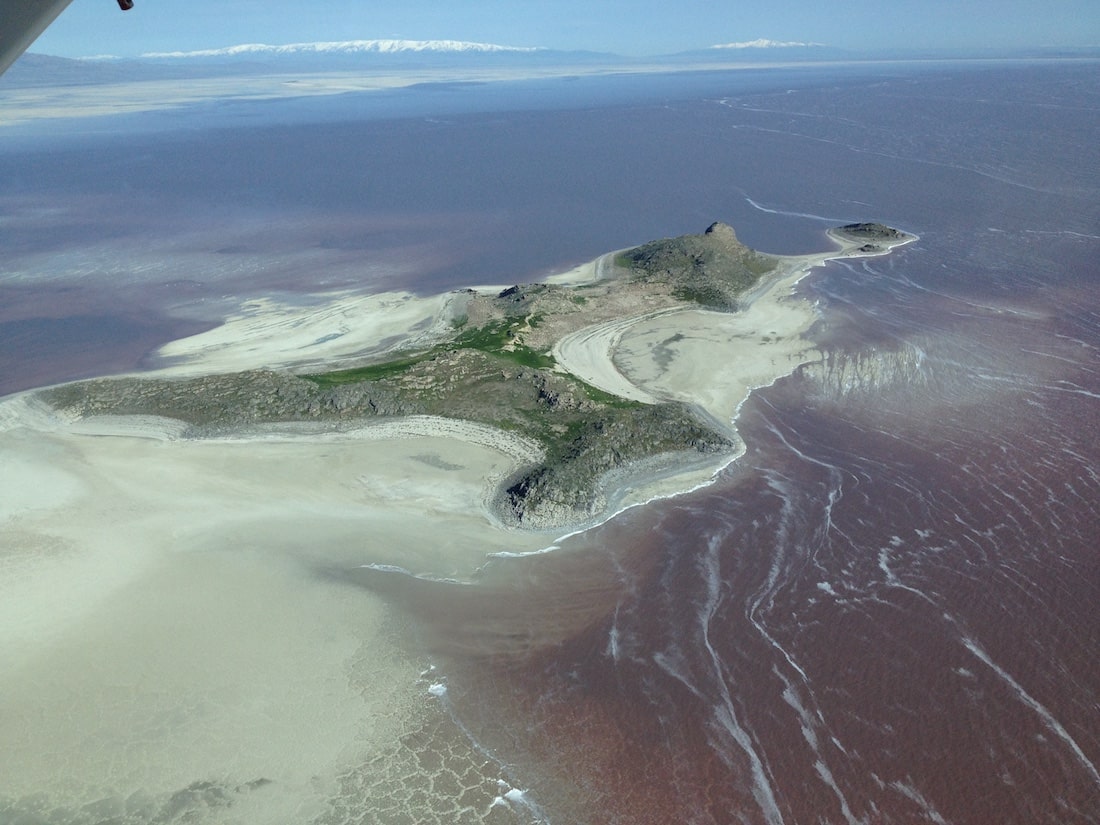 an island mostly surrounded by water, but connected an expanse of sand that tapers off frame