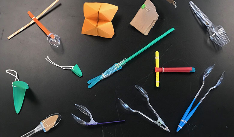 various pieces of everyday items arranged into beaks, including plastic forks and spoons, folded paper, and sticks