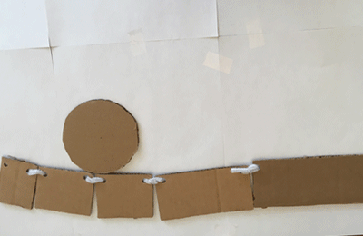 pieces of cardboard connected by string curling and uncurling