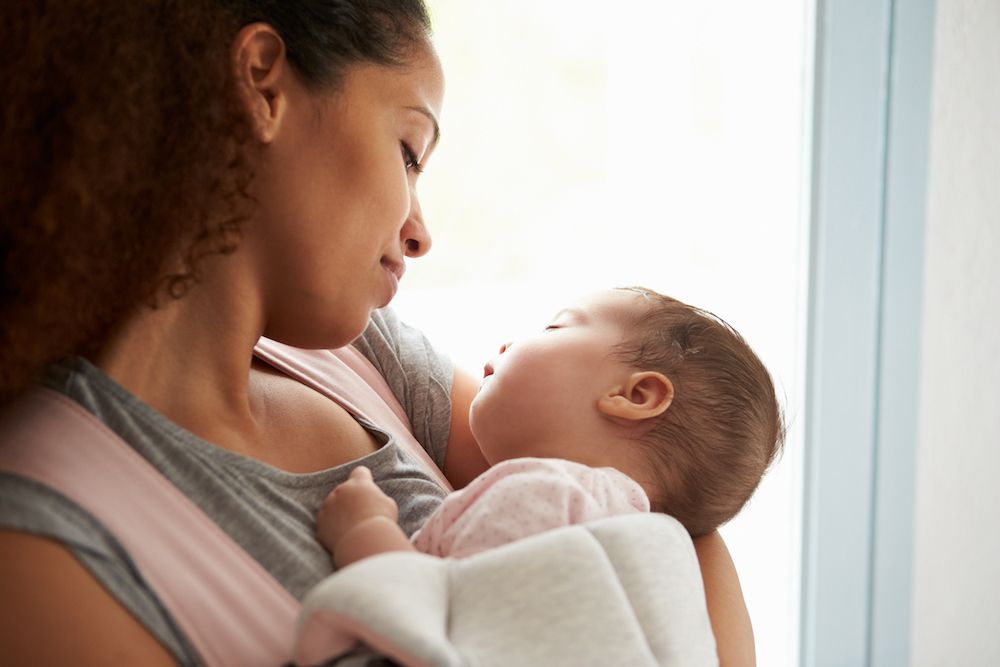 woman holding a baby close and looking at it