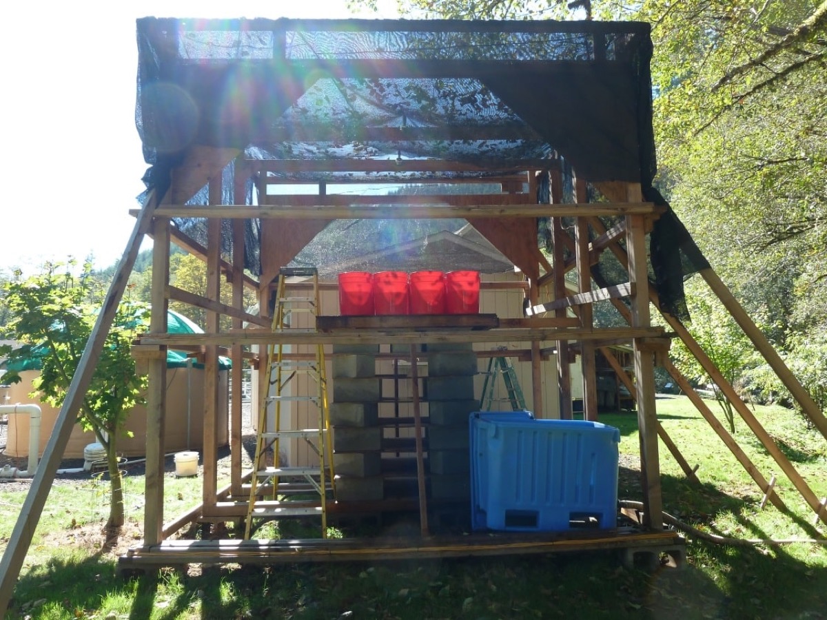 a wooden structure with magnetic coils and plastic buckets out in a grassy field