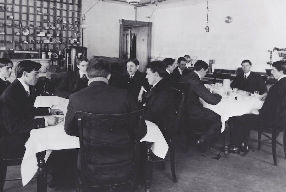 black and white photo of a bunch of men in suits sitting around tables