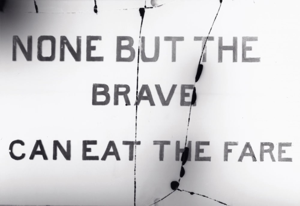 a black and white sign that reads "none but the brave can eat the fare."