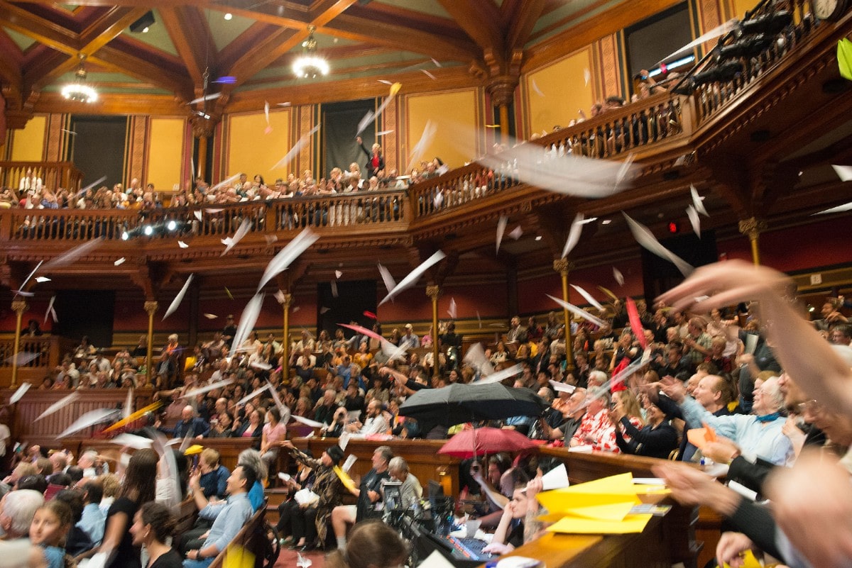 an audience in a theater toss paper planes