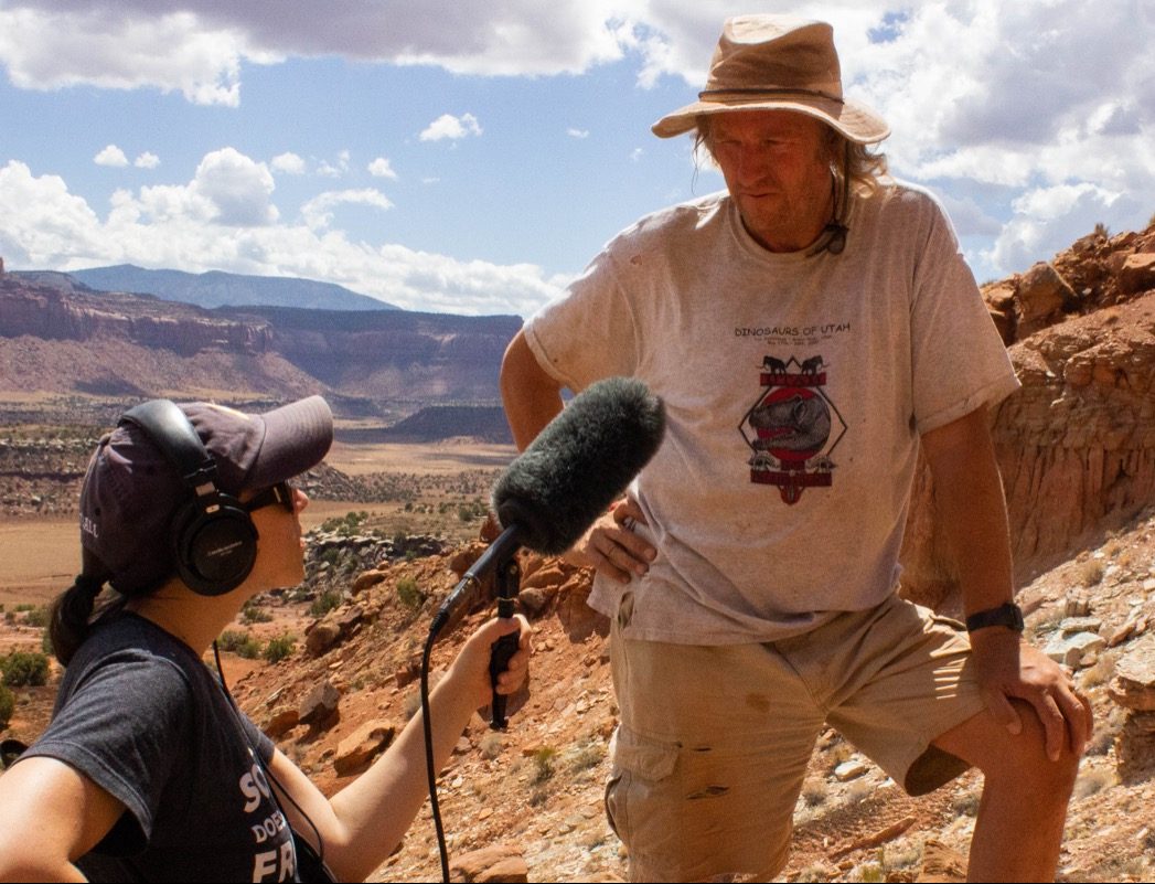 reporter katie hiler interviewing a male paleontologist on the side of a canyon