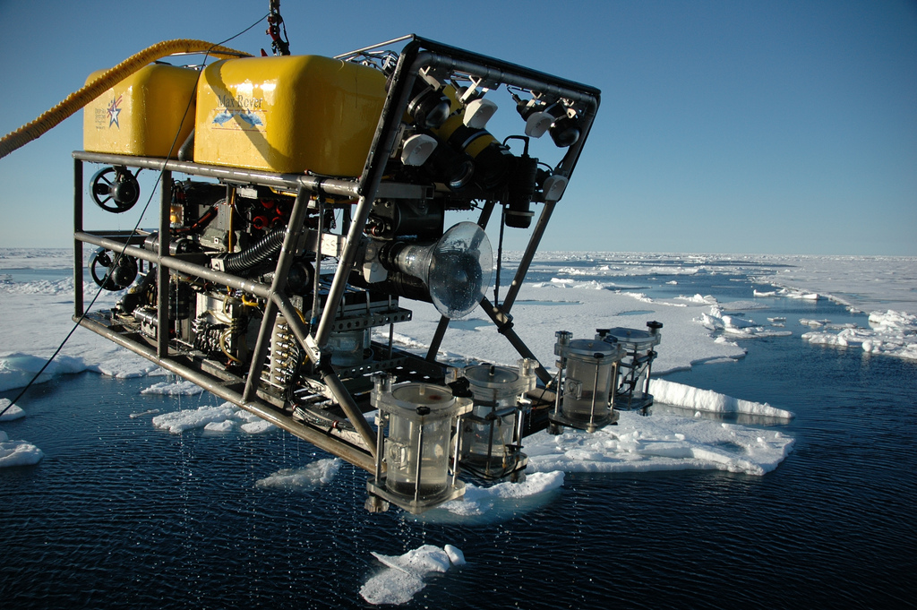 an rov on a crane with water samples, with a backdrop of sheets of ice over the ocean