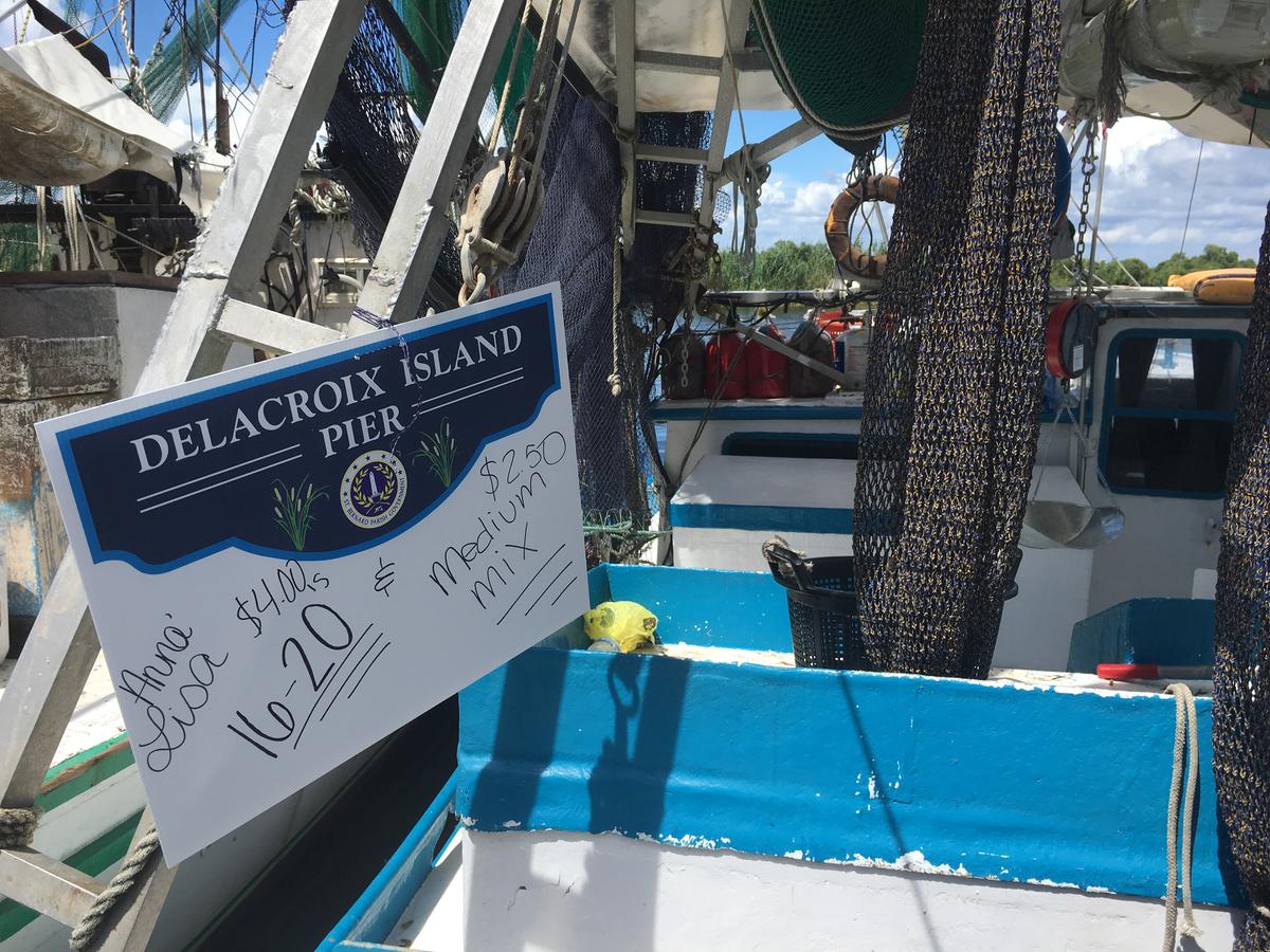 the back of a shrimper boat. there is a sign that reads "delacroix island pier" with different prices 