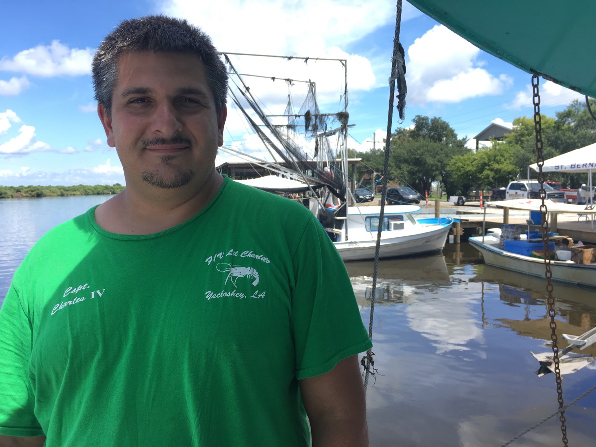 a man who is a shrimper stands on a dock in front of some boats