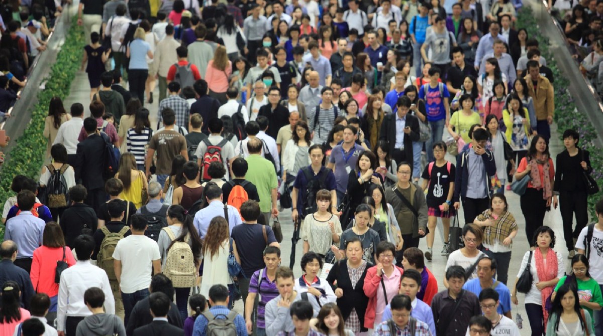 a crowd of people in hong kong going in and out of a tunnel in a subway station during rush hour