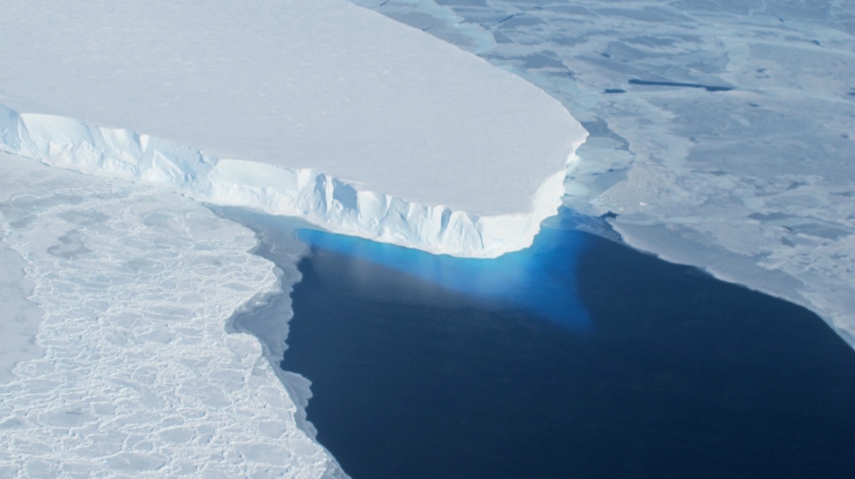 an arial shot of a large chunk of a glacier missing