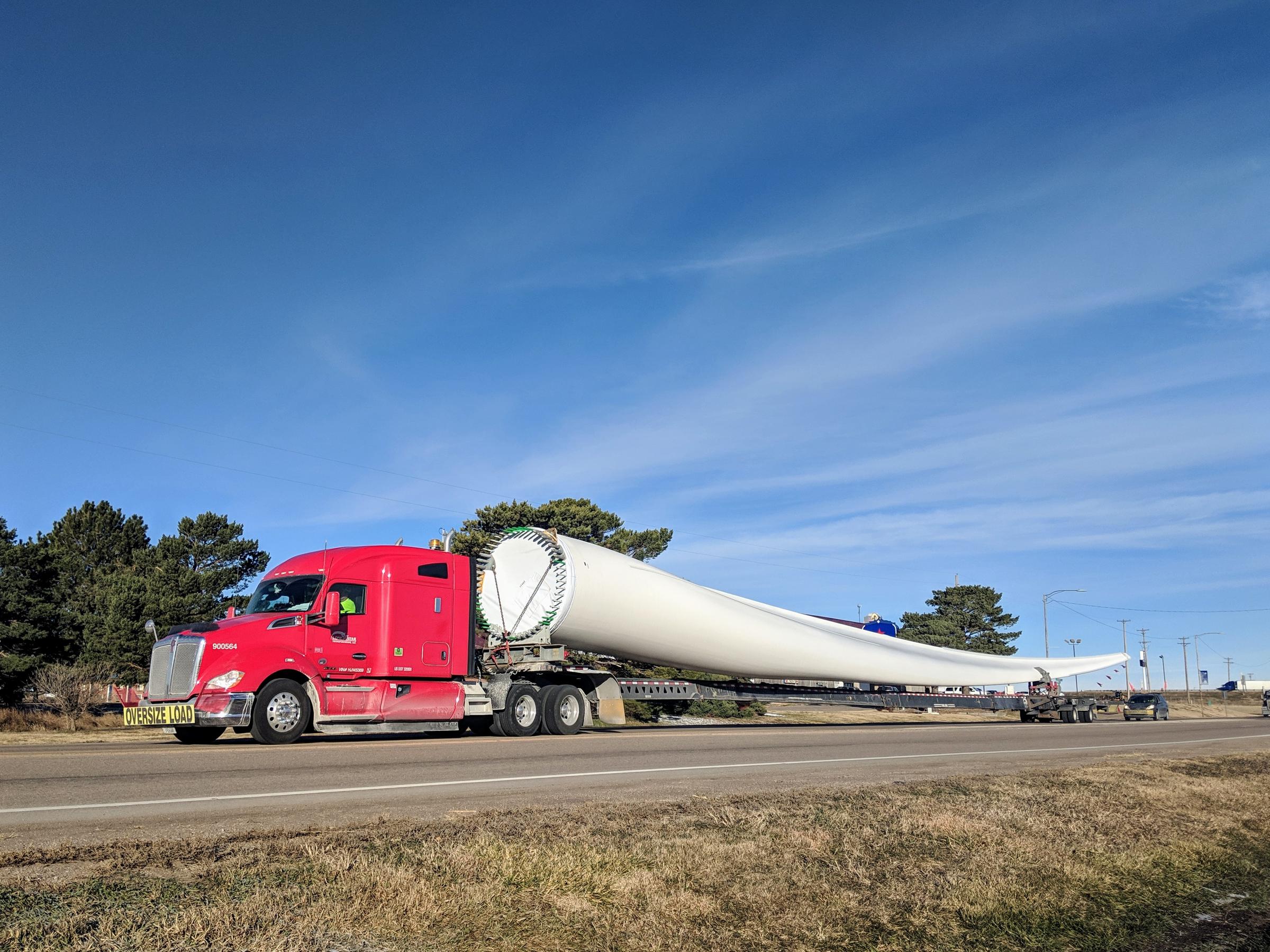 a truck carries a very long wind turbine on its bed