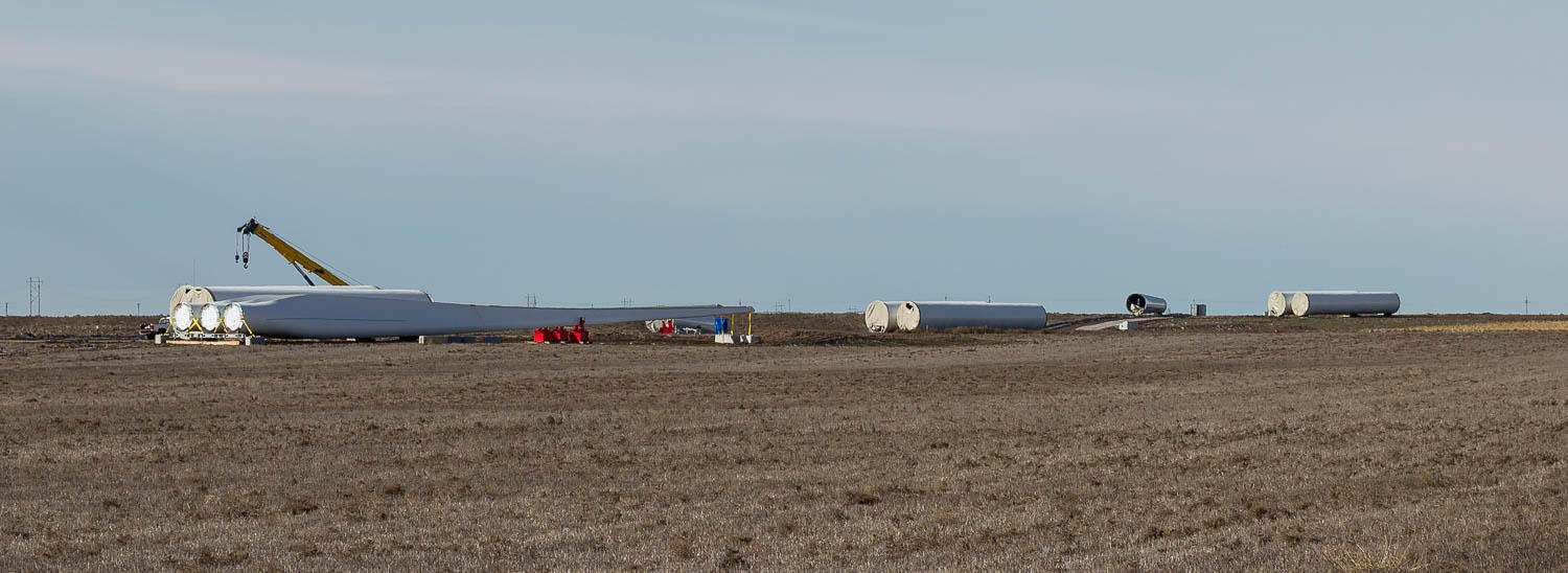 several long pieces of turbines laying on their sides in a field