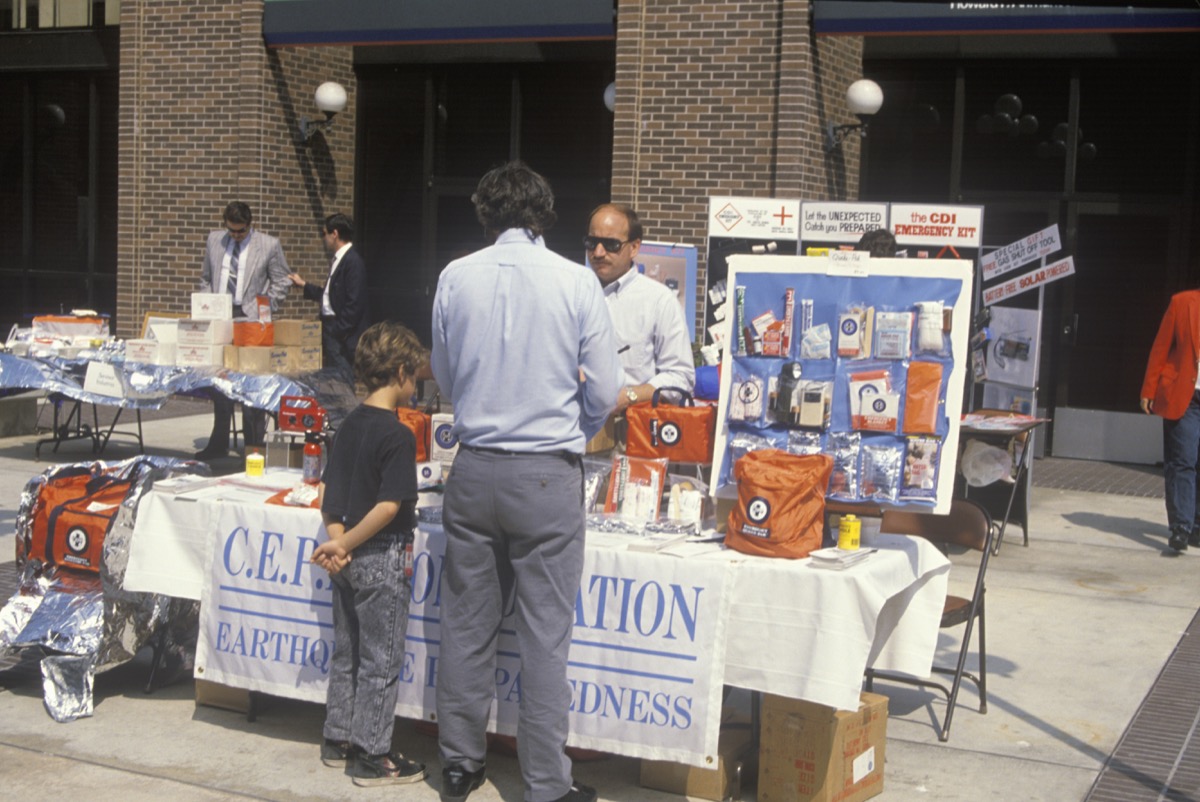 a man and a young boy at an earthquake preparedness table in Los Angeles in 1990