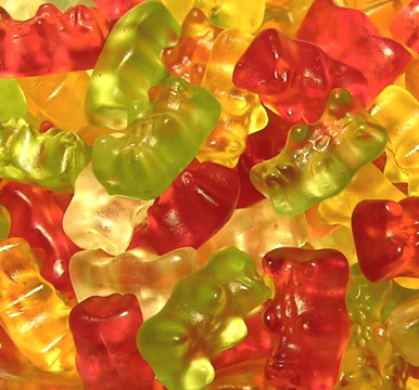 close up shot of yellow green and red gummy bears in a pile