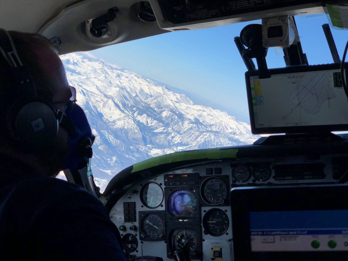 inside view of a person in an airplane observing snowpack from the window