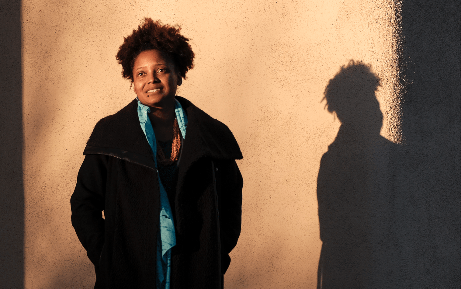 woman in jacket standing in front of wall