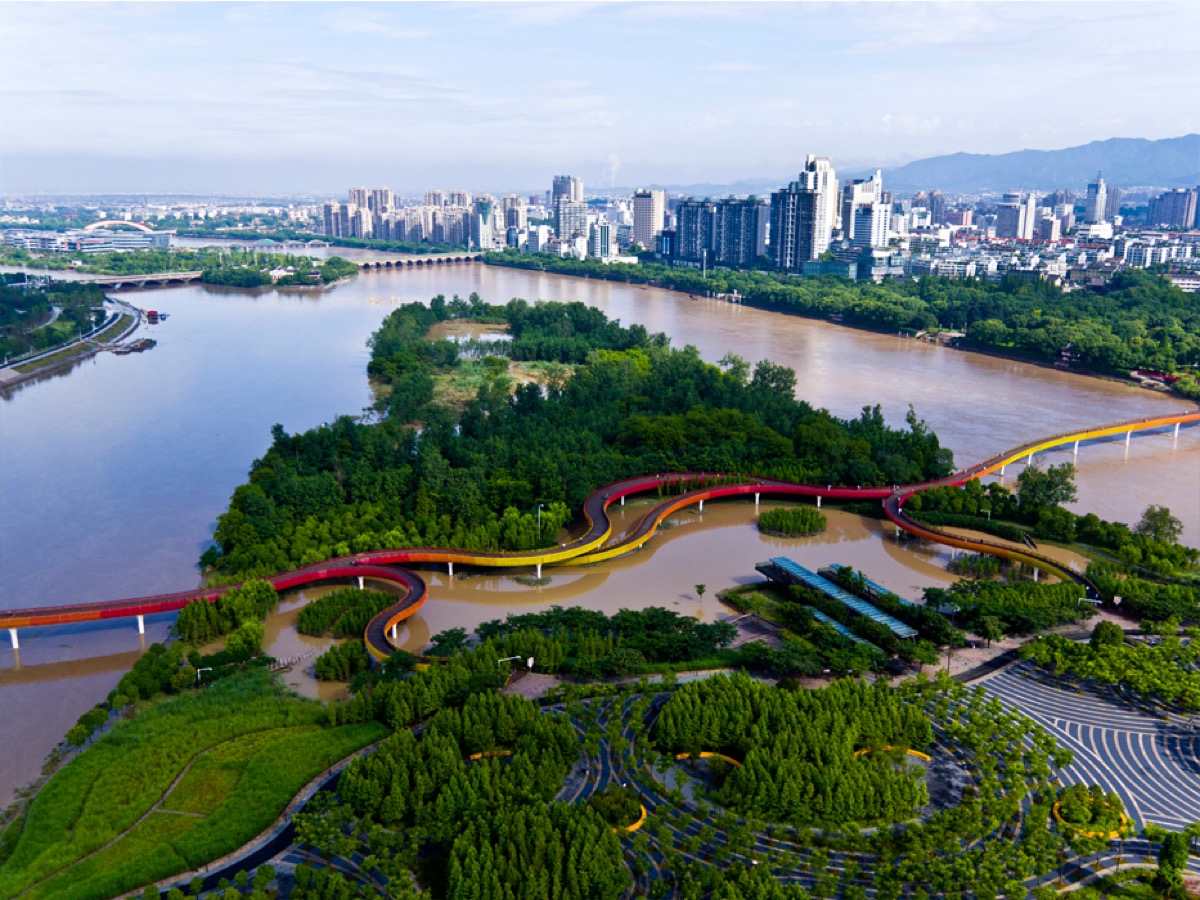 a park at the confluence of three rivers, with a colorful bridge in the foreground