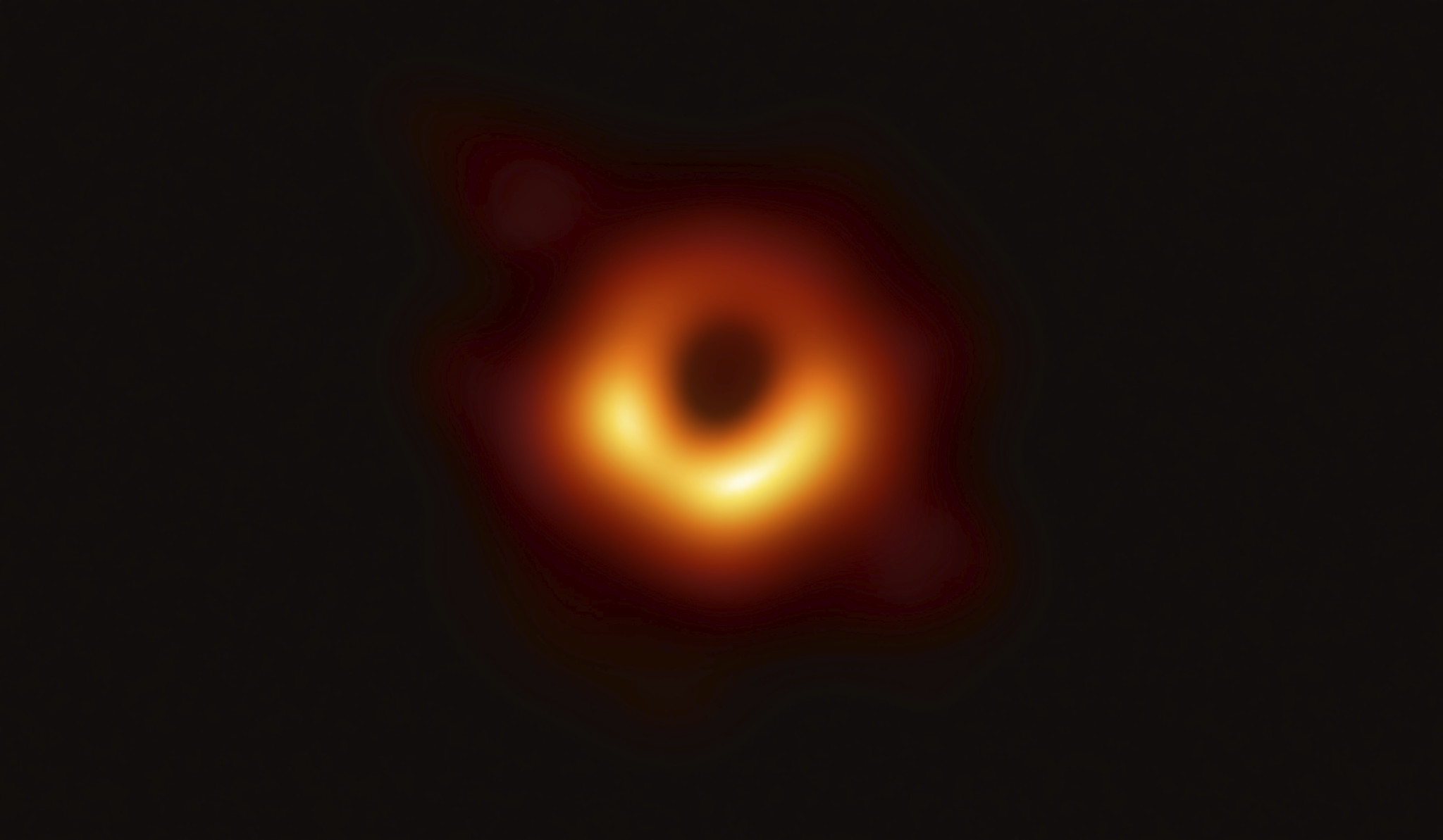 a orange glow surrounds a dark shadow, the black hole