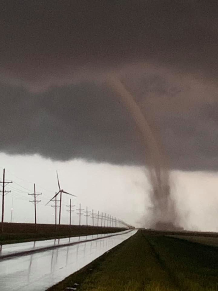 a tornado touching down next to a rural road, with a modern windmill