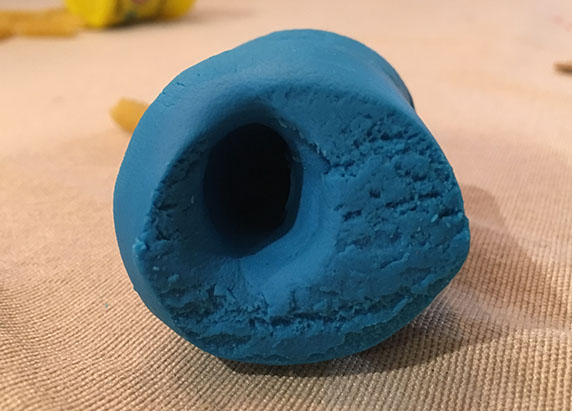 the same block of blue play-doh now with a hole inside