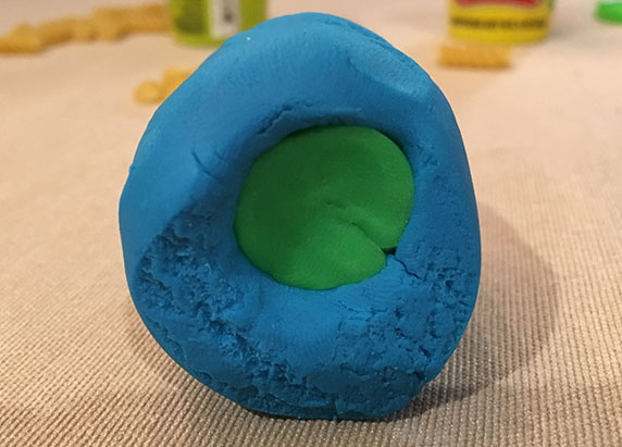 green play-doh rolled inside the blue play-doh block
