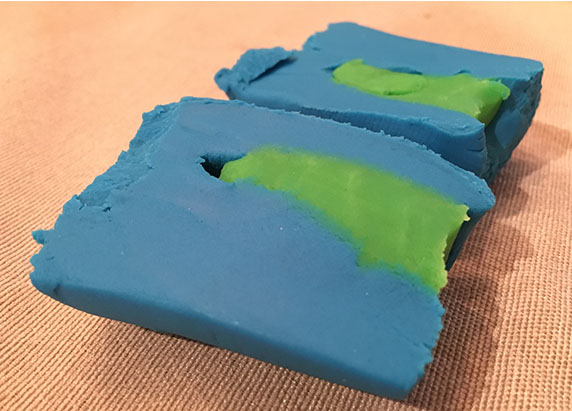 the block is cut in half, showing the inside of the play-doh like a cross section